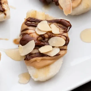 Close-up of a peanut butter banana bite with Nutella, honey, and toasted almond slices.