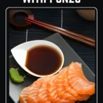 Thin slices of salmon sashimi served on a black plate with ponzu sauce and a small portion of wasabi.