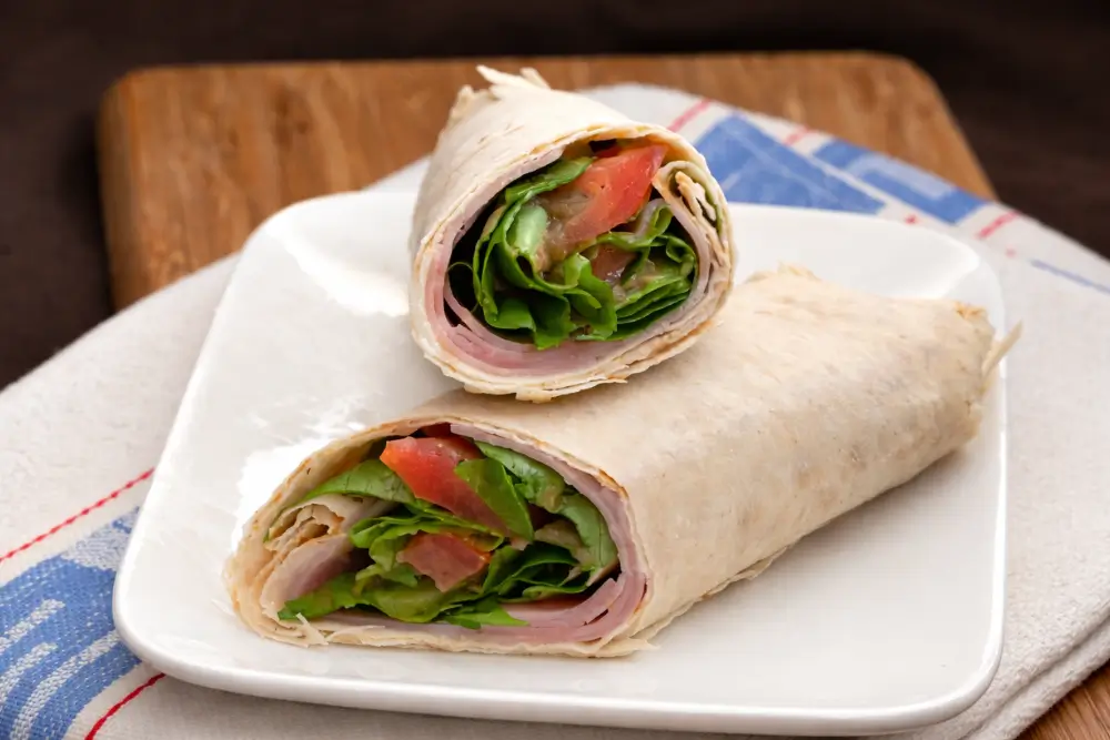 Ham Wrap with Lettuce and Tomato cut in half.