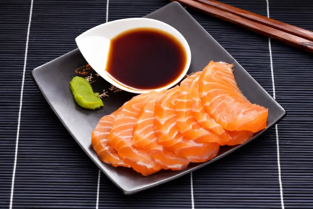 Salmon sashimi served with ponzu sauce and wasabi.