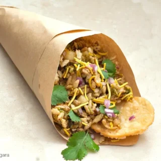 Bhel Puri served in a paper cone with sev, coriander and papdi.
