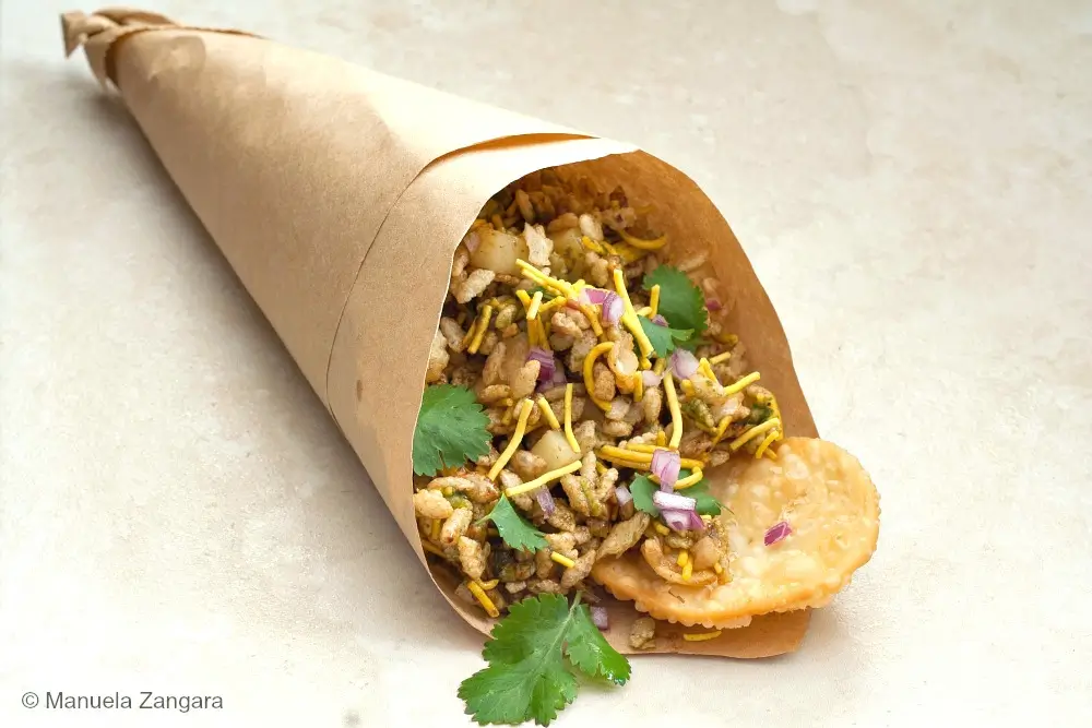 Bhel Puri served in a paper cone with sev, coriander and papdi.