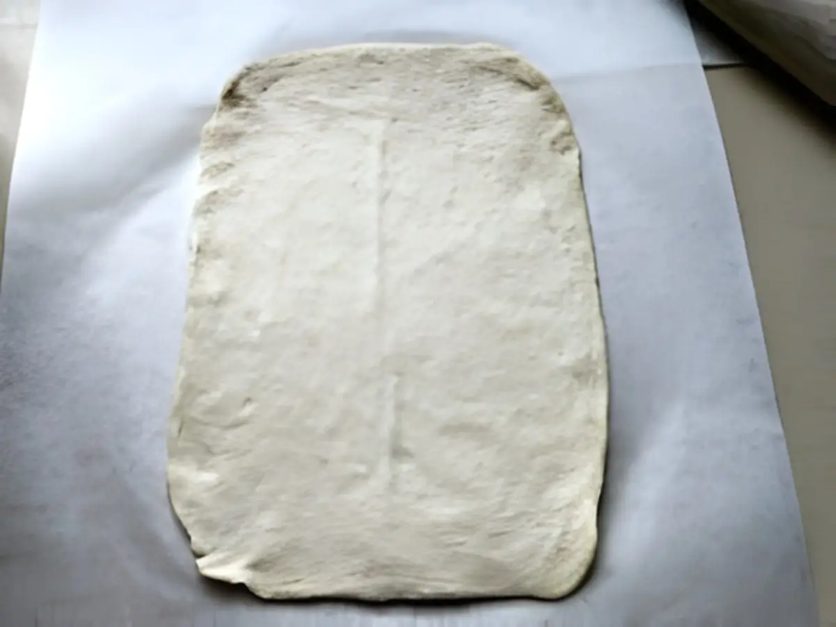 Rolled coca dough resting on baking paper before baking.