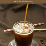 Hot coffee poured into a glass with ice and condensed milk for Vietnamese iced coffee.