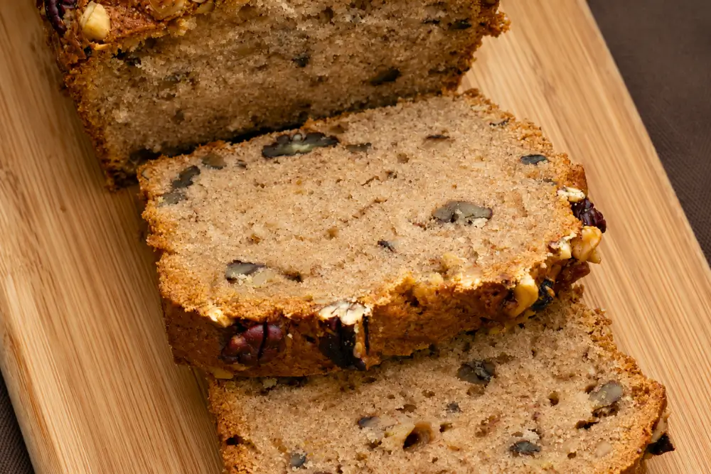 Close-up of moist banana loaf slices filled with chopped walnuts.