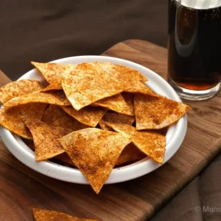 Close-up top view of baked homemade Doritos piled in a white bowl.
