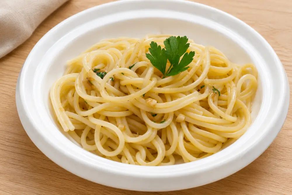 Close-up of Pasta con Aglietto e Prezzemolino with glossy spaghetti, garlic and fresh parsley.
