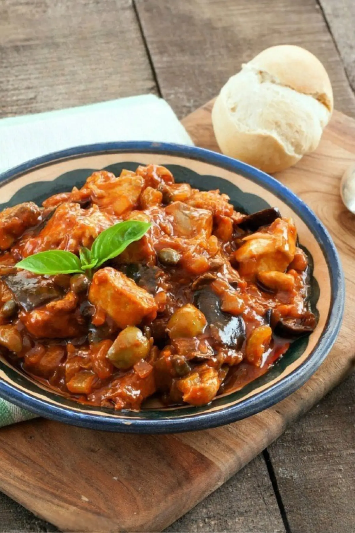 Swordfish Caponata served in a rustic bowl with basil garnish and warm bread.