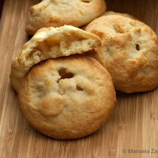 Pasta frolla cookies filled with apple, one cut open to show the tender apple centre.