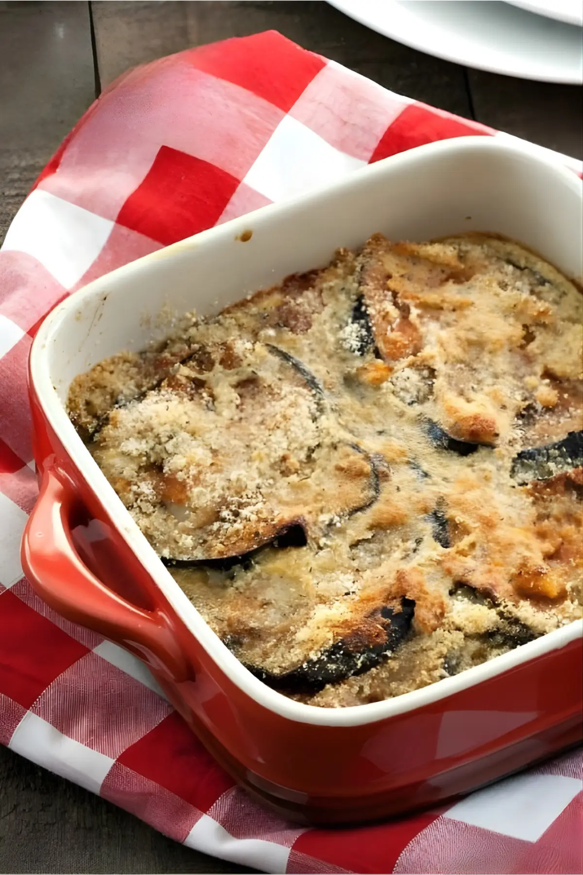 Freshly baked eggplant bake in a red casserole dish.