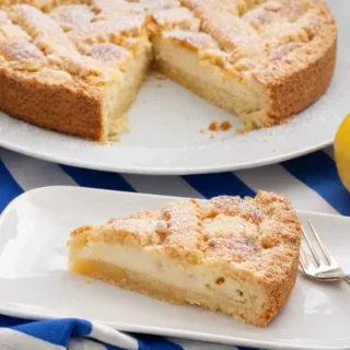 Slice of Pine Nut Cake with visible semolina layer served with lemon on the side.