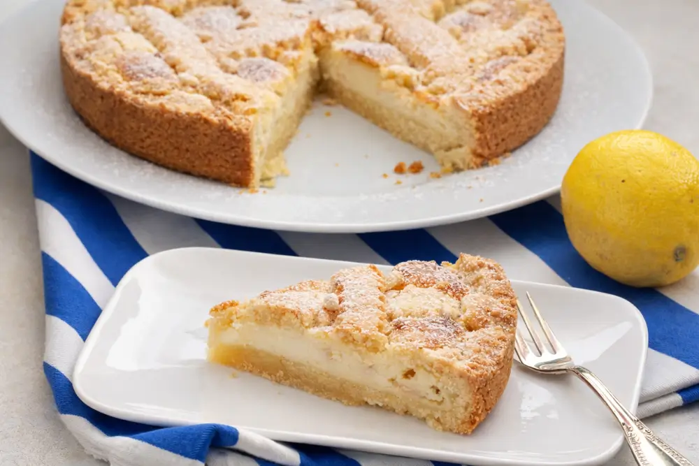 Slice of Pine Nut Cake with visible semolina layer served with lemon on the side.