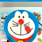 Doraemon fondant cake with red collar, yellow bell, and number 7 candle.