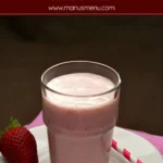 Pineapple strawberry apple smoothie with striped straw on plate.