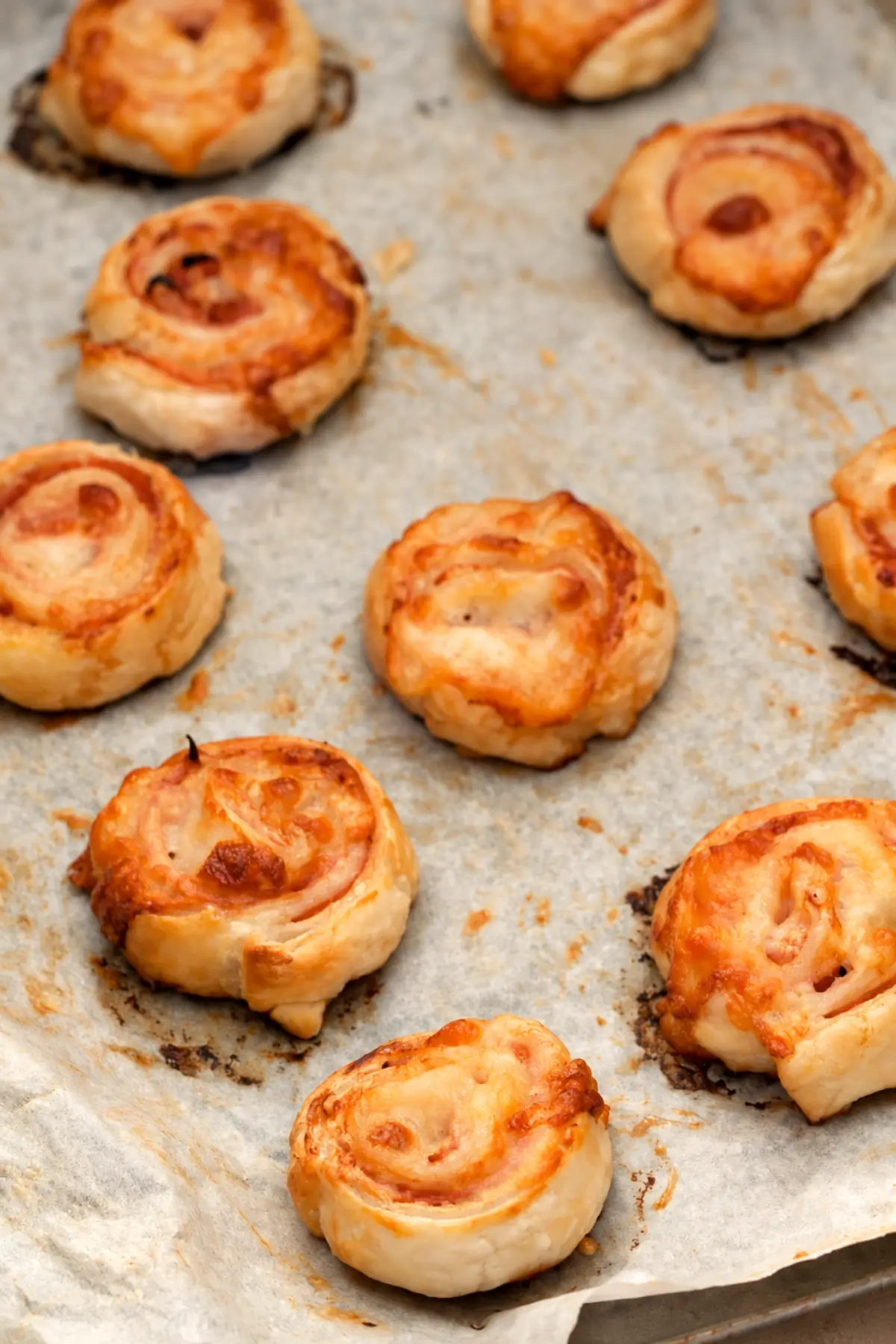 Golden puff pastry pinwheels baked on parchment paper.