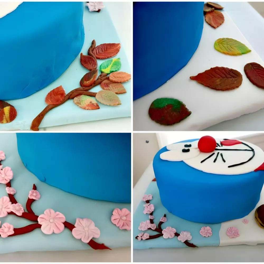 Cake board decorated with fondant cherry blossoms and autumn leaves around the Doraemon cake.