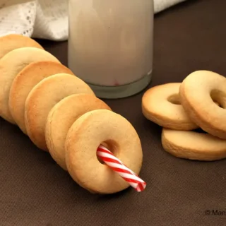 Macine cookies arranged on a table with a bottle of milk in the background.