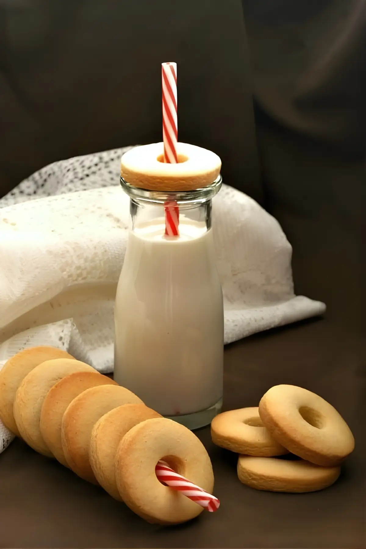 Macine biscuits stacked beside a glass bottle of milk with a striped straw.