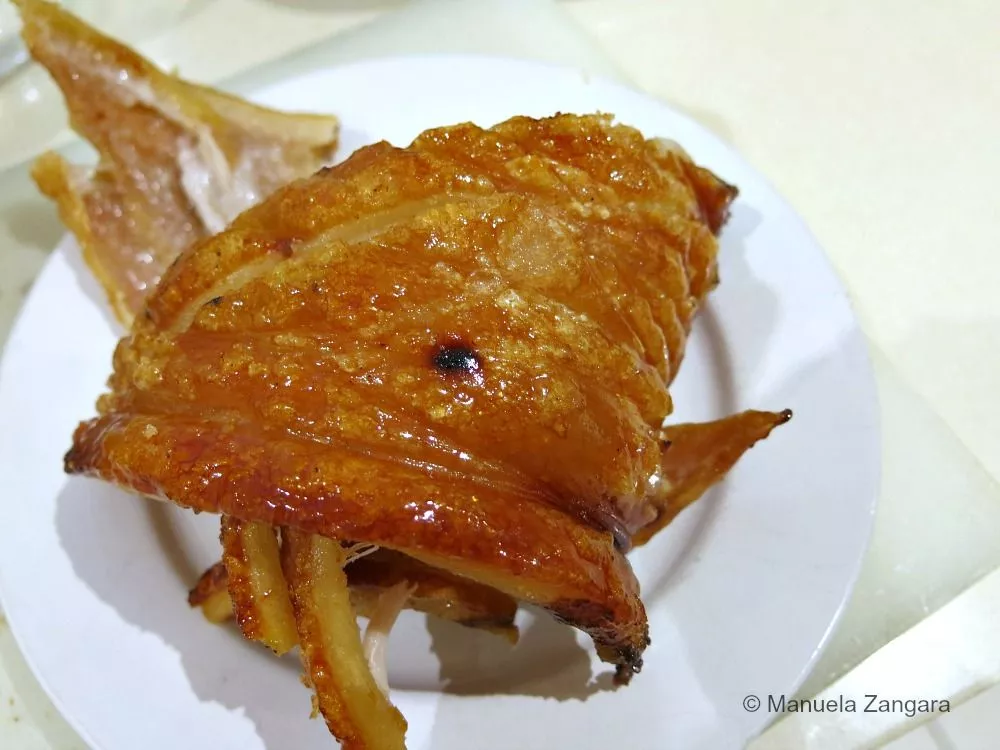 Golden, crispy pork crackling served on a white plate.