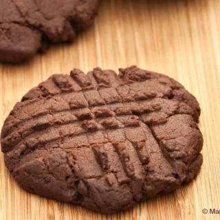 A few freshly baked chocolate buttercream cookies arranged on a wooden board.