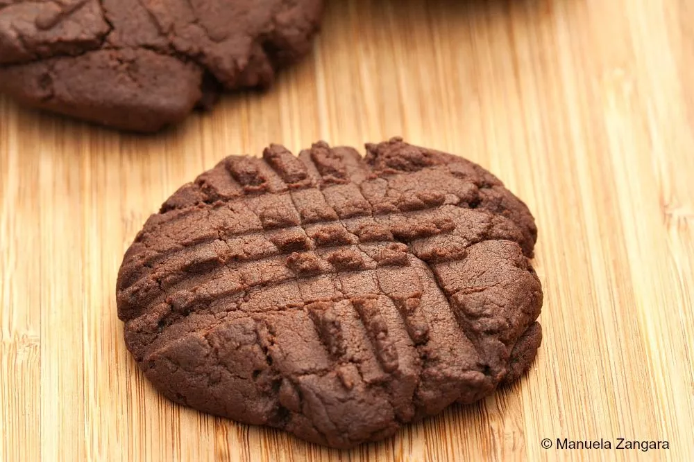 A few freshly baked chocolate buttercream cookies arranged on a wooden board.