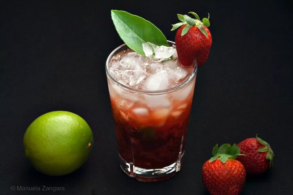 Strawberry Caipiroska cocktail with crushed ice, fresh strawberries, and a whole lime on the side.