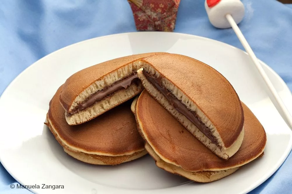 Soft homemade dorayaki pancakes with a smooth Nutella filling, served on a white plate.