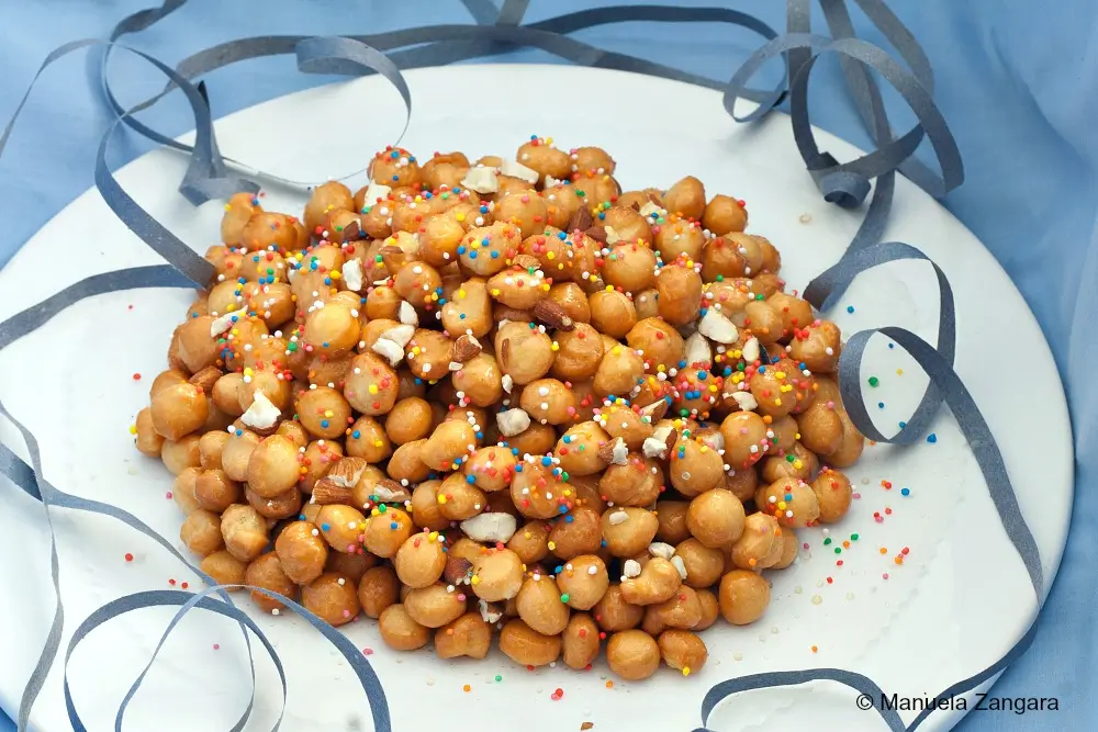 Close-up of Pignoccata honey balls topped with almonds and colourful sprinkles.