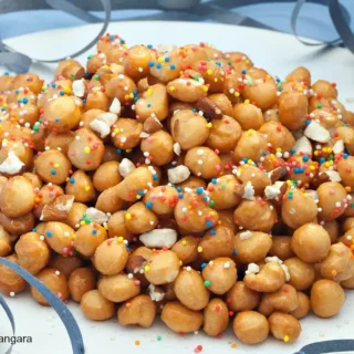 Finished Pignoccata shaped into a mound with almonds and sprinkles.