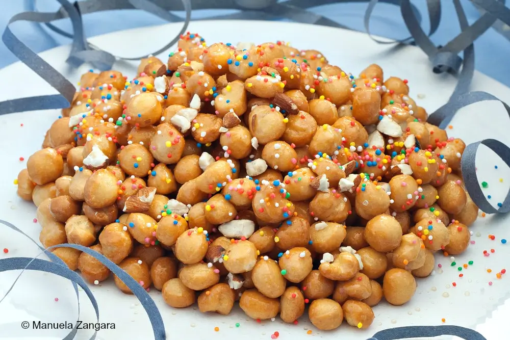 Finished Pignoccata shaped into a mound with almonds and sprinkles.
