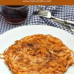 Crispy fried spaghetti cake on a white plate over a checkered cloth.