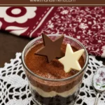Triple chocolate mousse layered with chocolate cake and topped with cocoa powder and chocolate stars in a glass dessert cup.