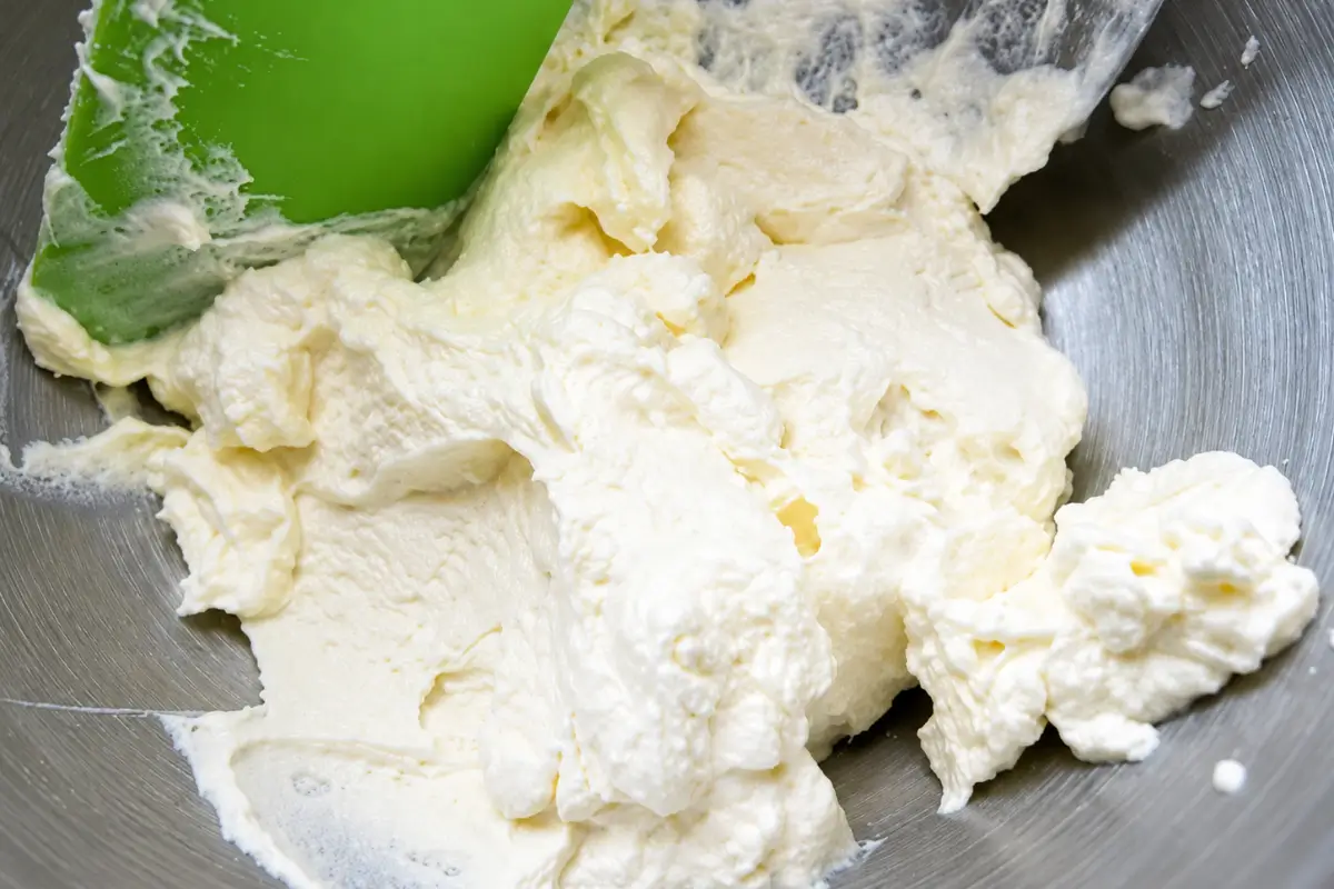 Thickened cream being folded with a spatula until light and fluffy.