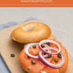 Open smoked salmon bagel topped with red onion rings and capers.