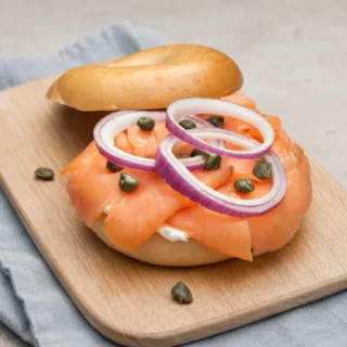 Open smoked salmon bagel topped with red onion rings and capers.