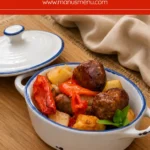 Baked Italian sausage with golden potatoes, red bell peppers and fresh basil in a white dish.