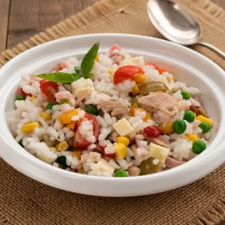 Italian Rice Salad served in a bowl with tuna, ham, Swiss cheese, vegetables and fresh basil.