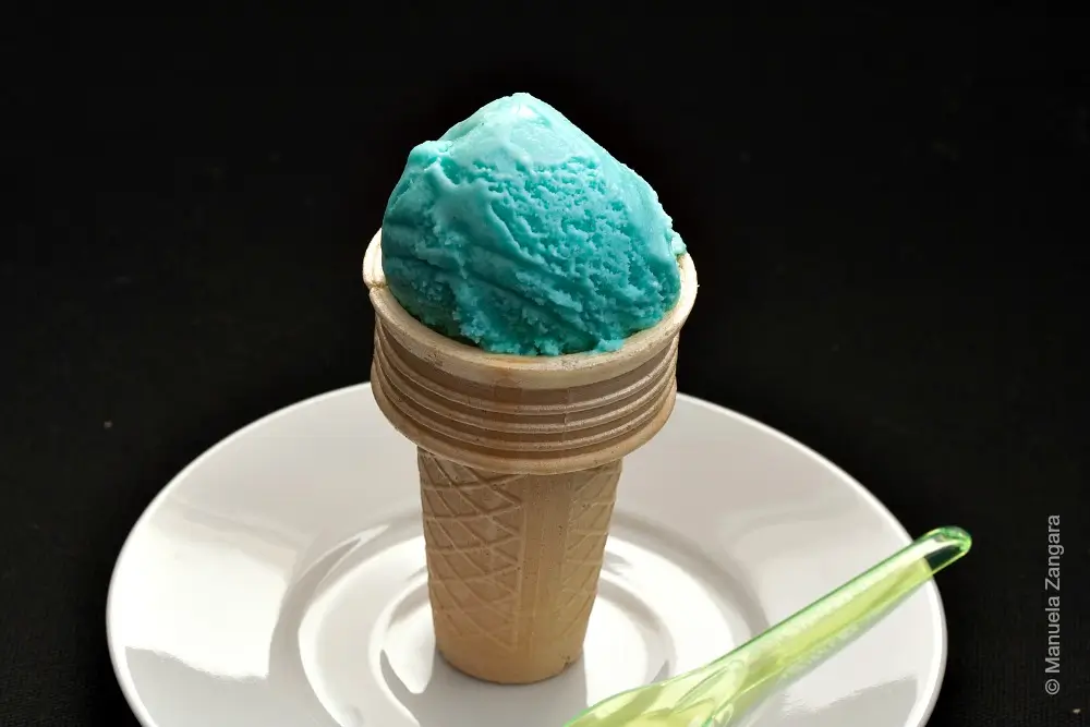 Close-up of a blue Gelato al Puffo scoop in a wafer cone.