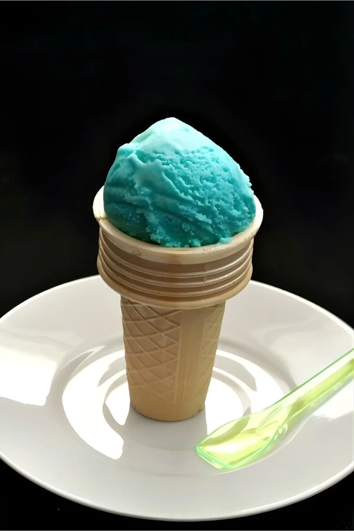 Blue Gelato al Puffo served in a wafer cone on a white plate.