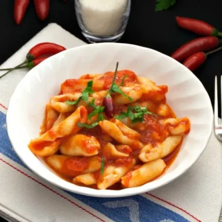 Bowl of cicatelli pasta coated in spicy tomato sauce.
