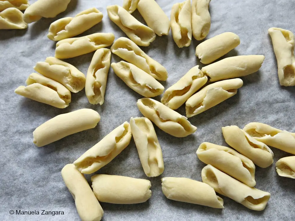 Hand-shaped cicatelli arranged on a floured tray.