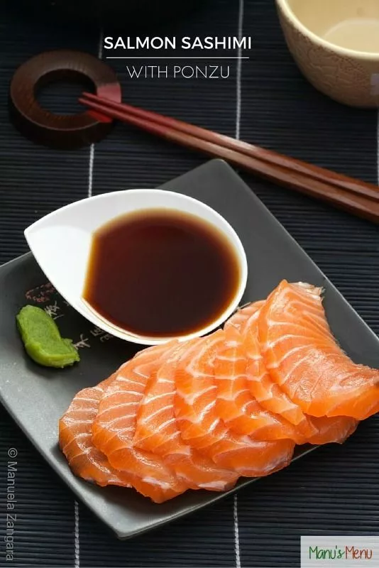 Slices of fresh salmon sashimi served with ponzu sauce and wasabi on the side.
