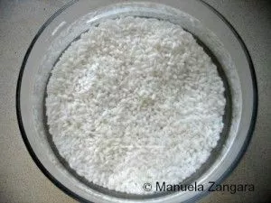 Sushi rice soaking in a glass bowl of water before cooking.