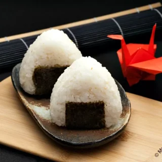 Two triangle onigiri wrapped with nori on a plate.