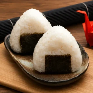 Two Tuna Mayo Onigiri wrapped with nori and served on a plate.