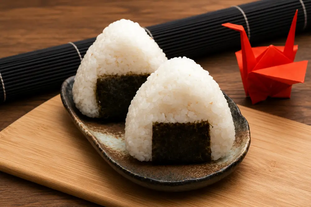 Two Tuna Mayo Onigiri wrapped with nori and served on a plate.
