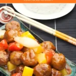 A close-up of Chinese sweet and sour pork meatballs with red peppers, pineapple, and onions served in a dish.