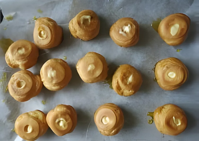 Caramel-dipped cream puffs set on baking paper before assembling the Croquembouche tower.