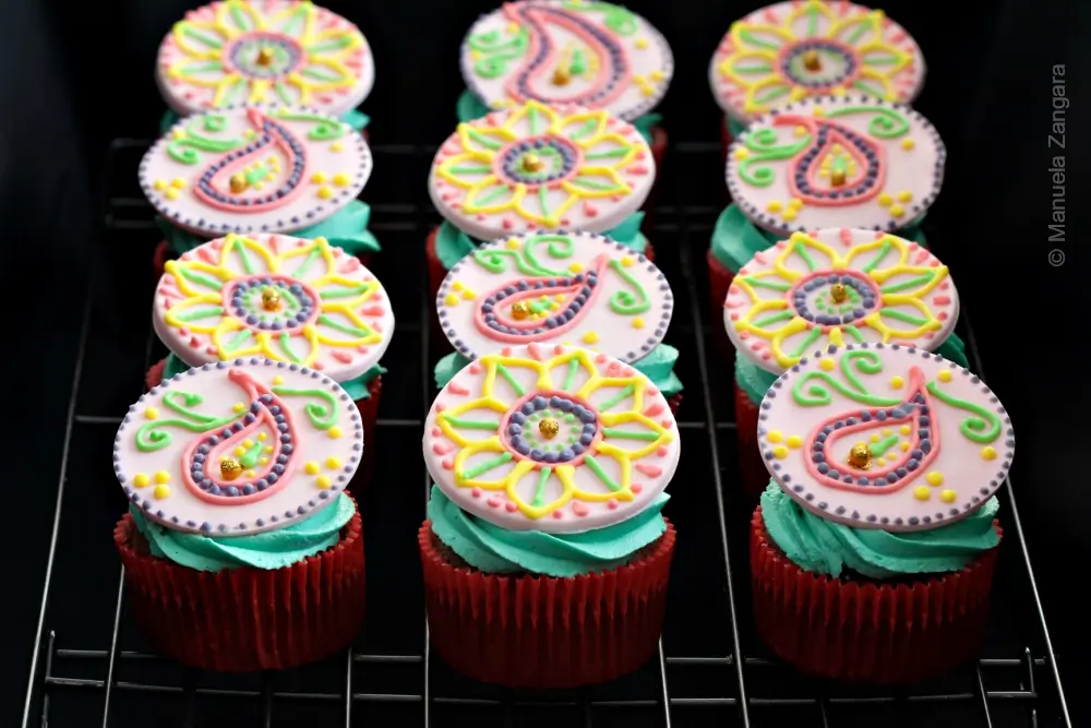 Tray of chocolate cupcakes decorated with colourful fondant patterns and buttercream swirls.