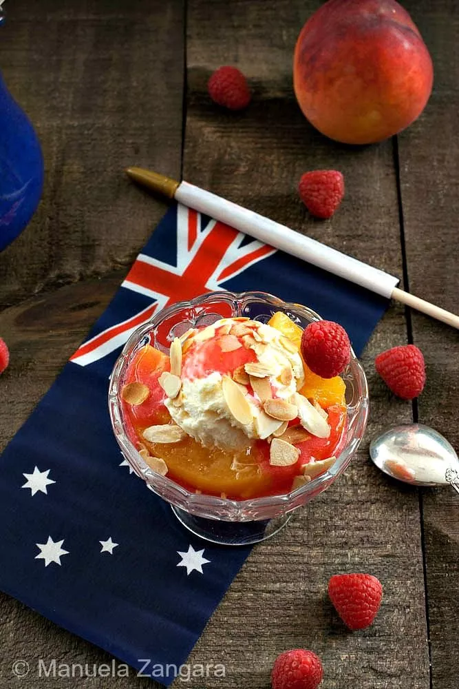 Peach Melba dessert topped with ice cream, almonds, and raspberries on an Australian flag napkin.